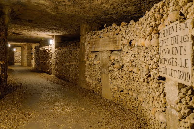 A corridor in the Catacombs of Paris lined with skulls and bones